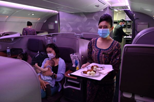 2020年10月24日，新加坡航空空客A380飛機上空姐微笑著在商務艙提供食物。