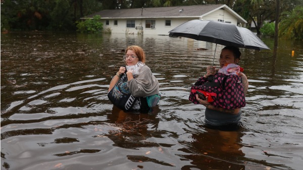 2023 年8 月30 日，佛罗里达州塔彭斯普林斯，飓风伊达利亚的洪水淹没了他们的家，马卡特拉・里奇特（左）和她的母亲Keiphra Line 不得不撤离家园，涉水穿过洪水。飓风伊达利亚正在袭击佛罗里达州的大本德地区。(Joe Raedle/Getty Images)