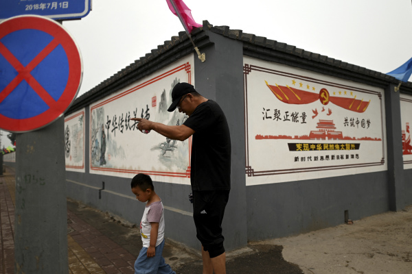 2021年6月9日，一名男子走過北京街頭的宣傳壁畫，上面寫著「凝聚正能量，共筑中國夢」。