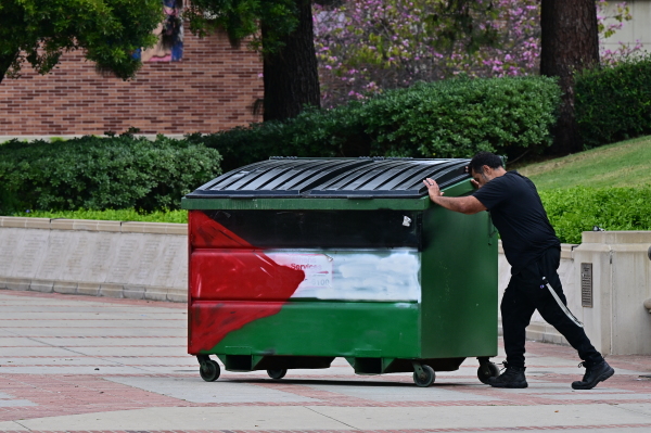 2024年5月2日清晨，在加利福尼亚州洛杉矶，警察驱逐支持巴勒斯坦的学生后，一名男子在加州大学洛杉矶分校（UCLA）校园内推着一个涂有巴勒斯坦国旗颜色的垃圾桶。